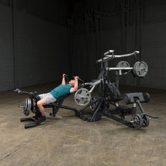 Individual using the Body-Solid leverage gym frame for a strength workout with weights in a spacious gym setting.