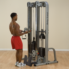 Man exercising on a PCL Dual Cable machine with dual 160 lb weight stacks for strength training.
