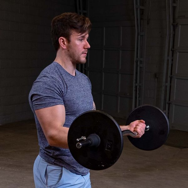 Man lifting 7.5lb black standard weight plates for strength training in a gym setting.