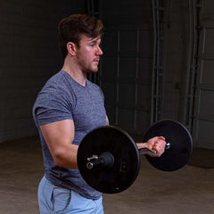 Man lifting 7.5lb black standard weight plates for strength training in a gym setting.